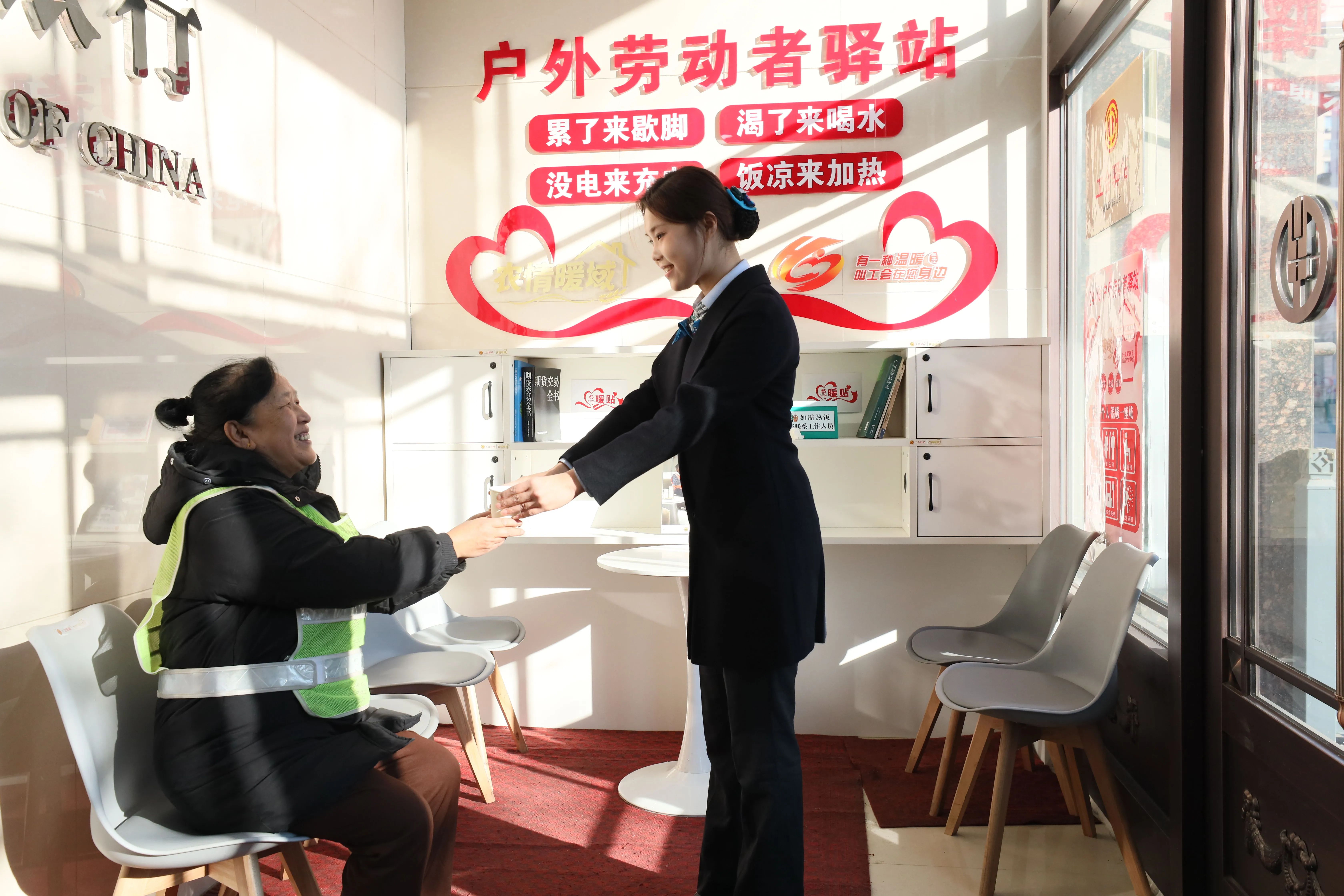 黑龙江农垦宏博支行客户经理为冬日前来户外劳动者驿站歇脚的环卫工人送上热水。徐云皓摄影报道