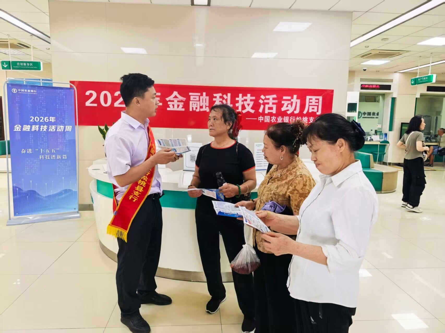 贵州铜仁分行员工在网点为客户讲解手机银行、“惠农 e 贷”等线上金融产品，同步科普防范新型电信网络诈骗知识。 龙松文摄影报道