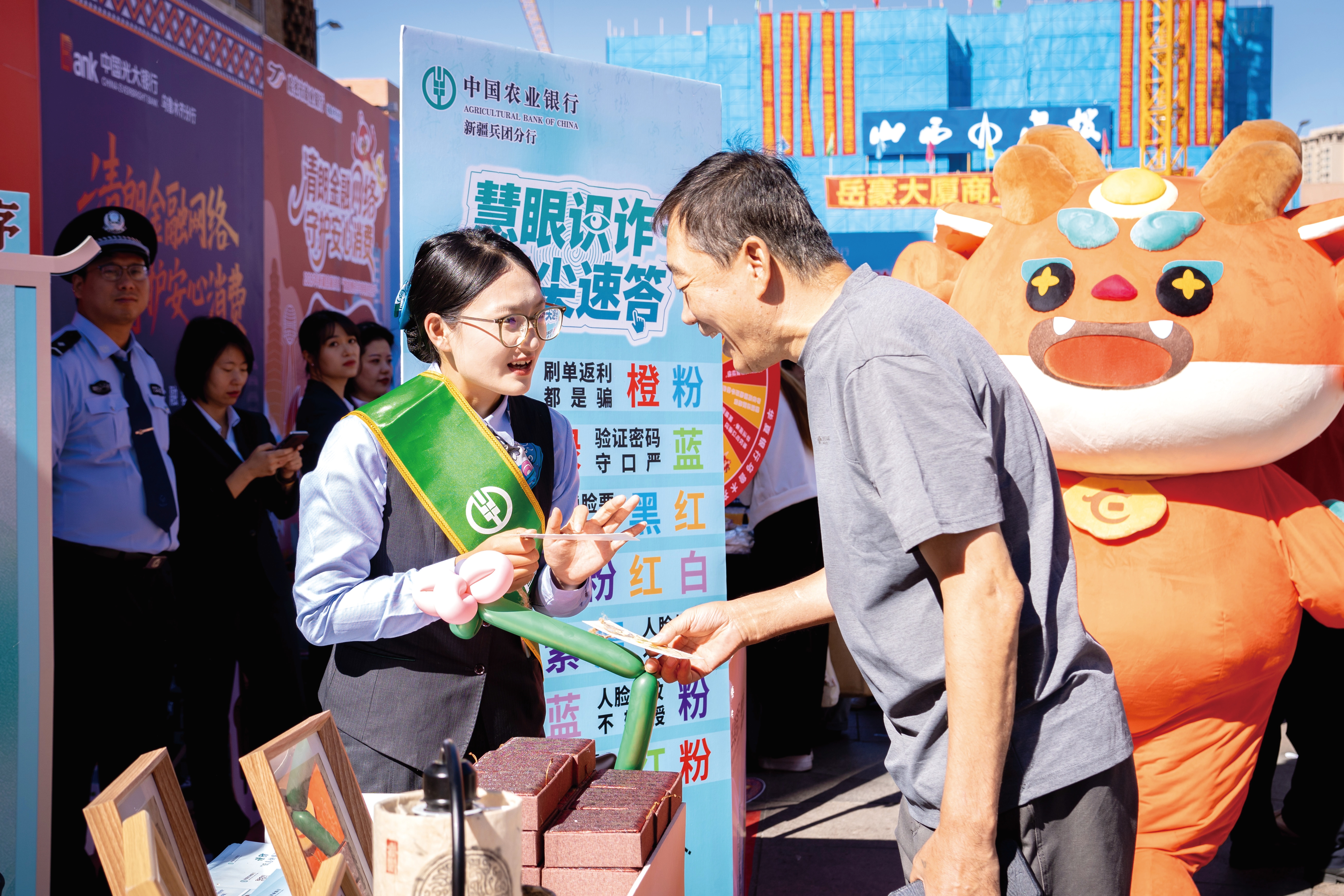 图为新疆兵团分行工作人员向咨询群众耐心讲解养老诈骗、虚假理财诈骗的识别要点和防范技巧。