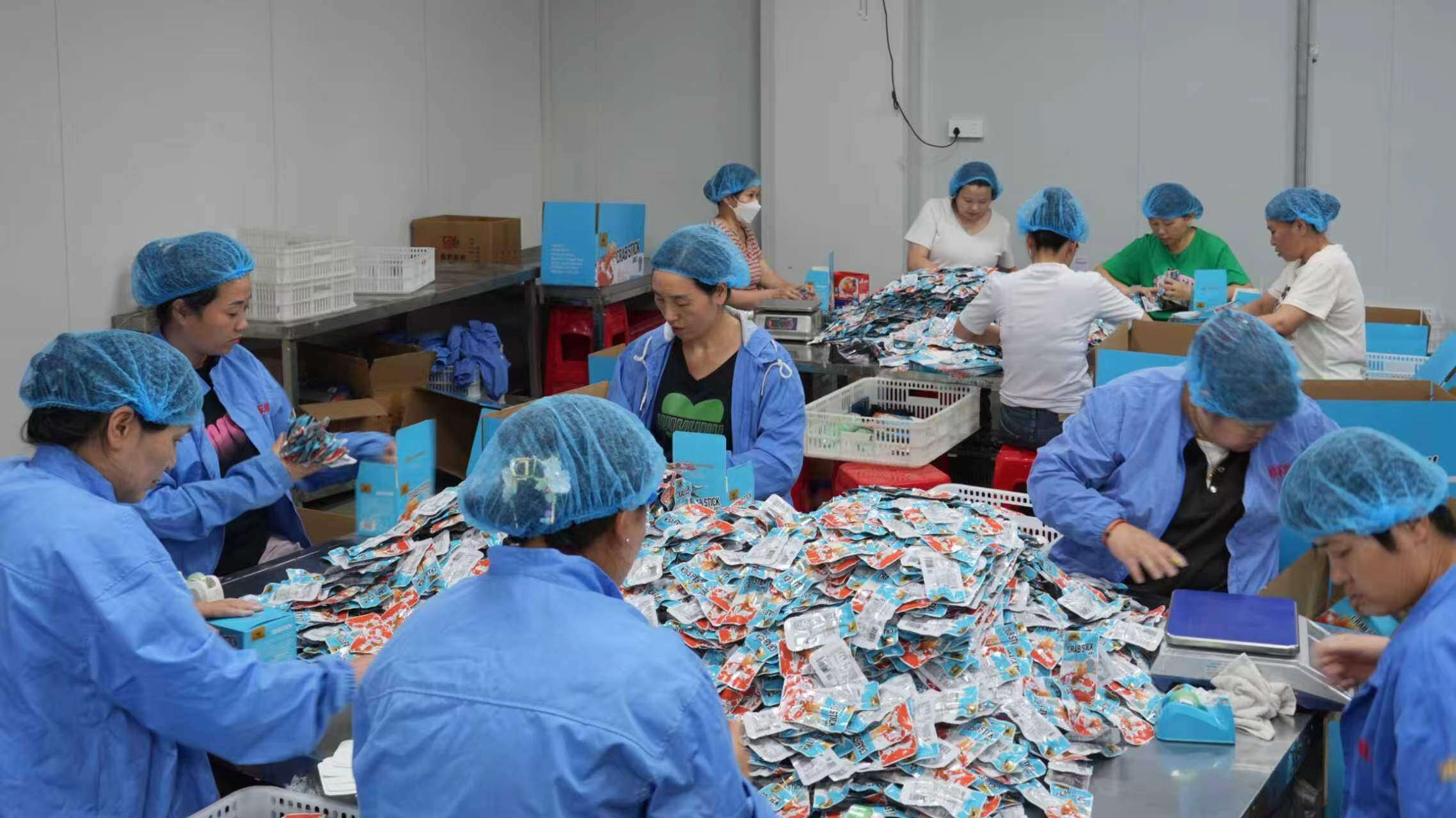 工人正在分装、打包休闲食品。摄影:苏炳秋 工人正在分装、打包休闲食品。摄影:苏炳秋
